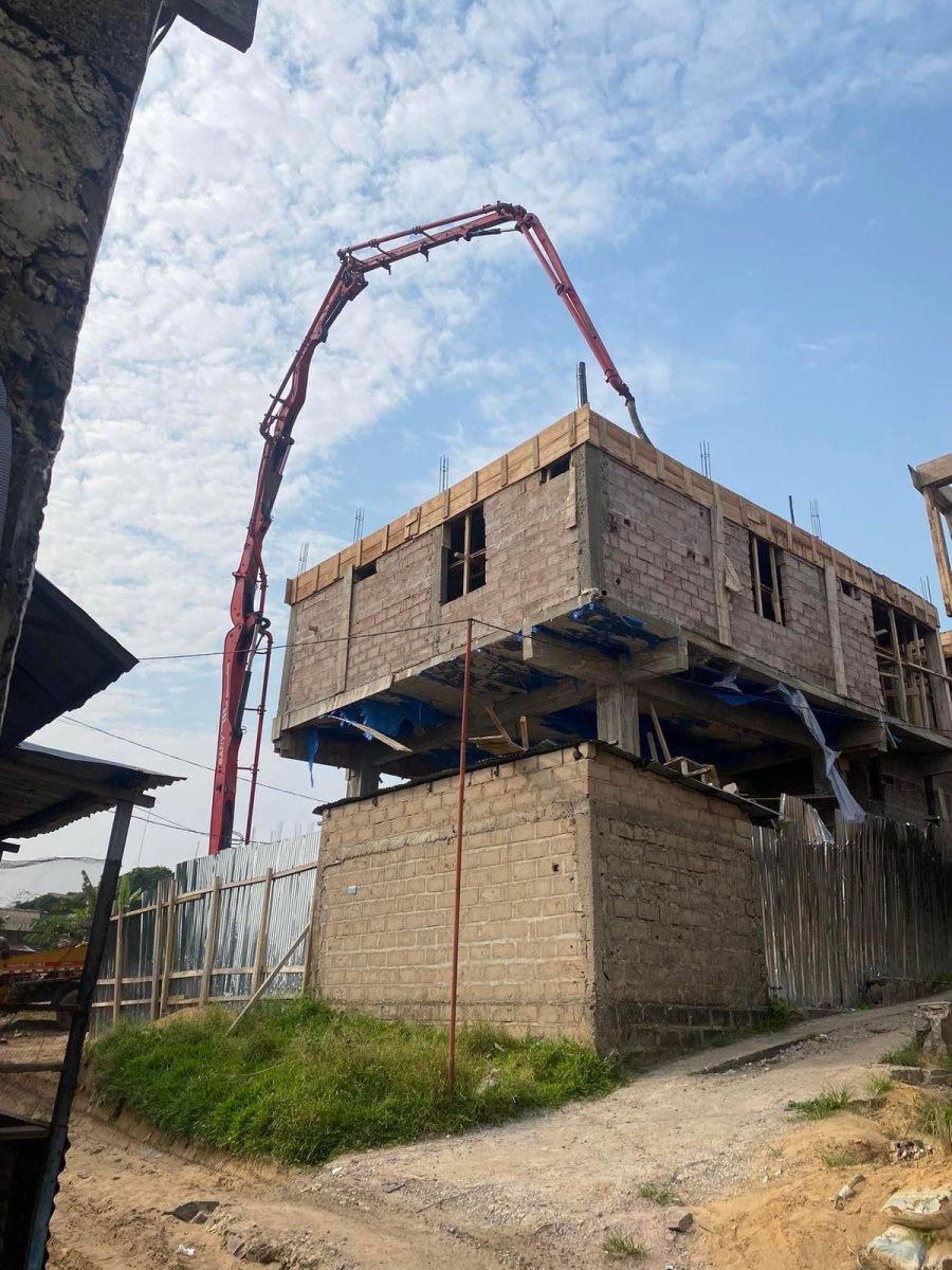 Pompe à béton déployée au-dessus d'une maison à étage en construction, vue d'en bas