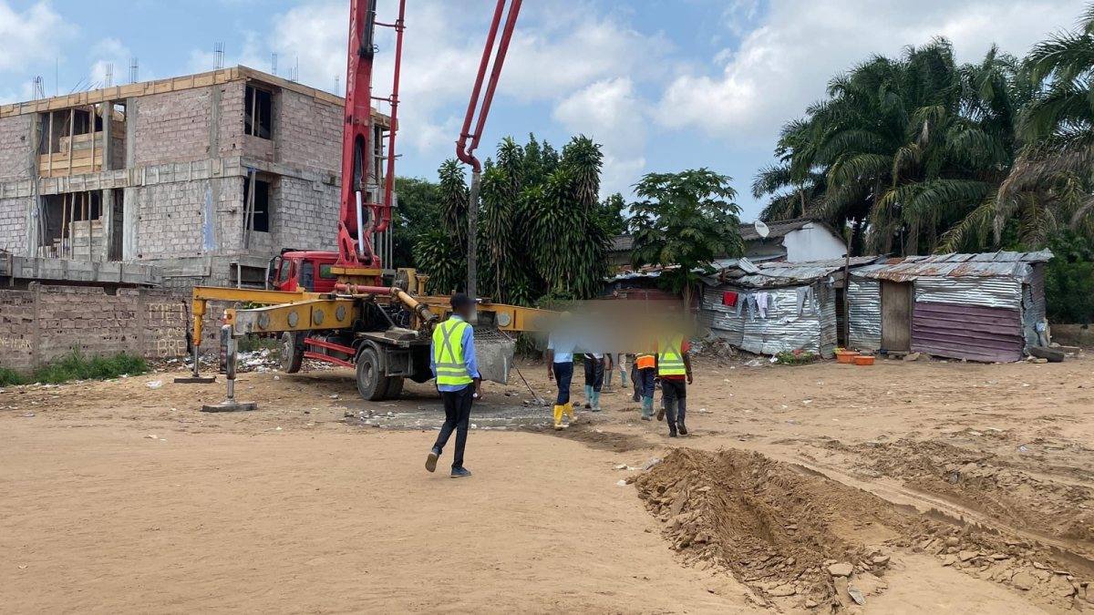 Équipe marchant vers le camion pompe à béton, immeuble en construction à gauche