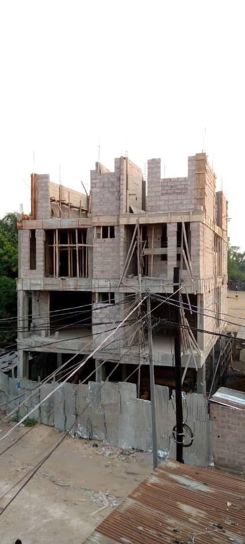 Immeuble de trois niveaux en blocs de béton, coffrages en bois en haut