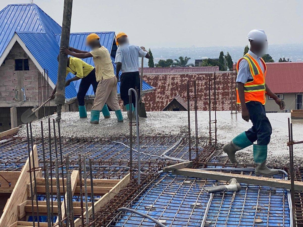Coulage d'une dalle de béton, ouvriers avec pelles et responsable en gilet orange