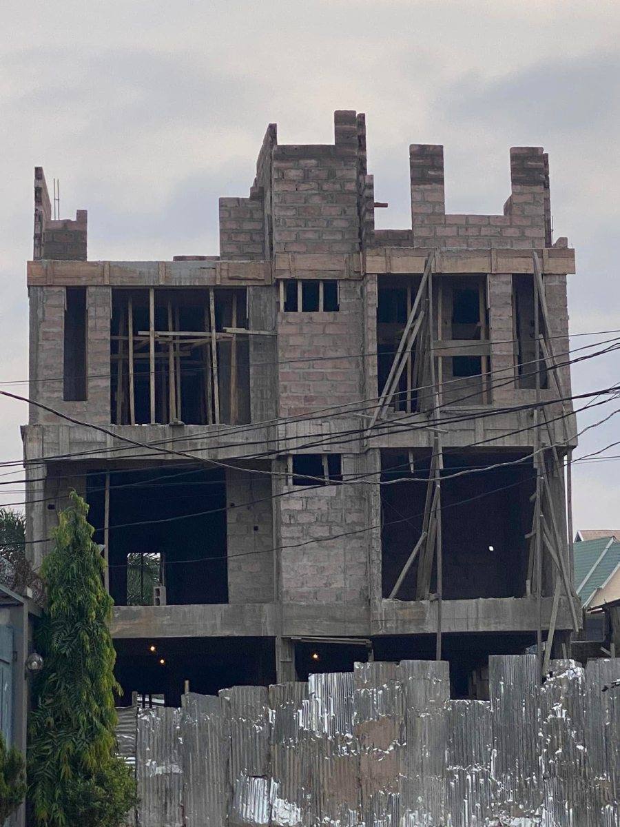 Immeuble à étages en blocs de béton, vue de face derrière une clôture en tôle