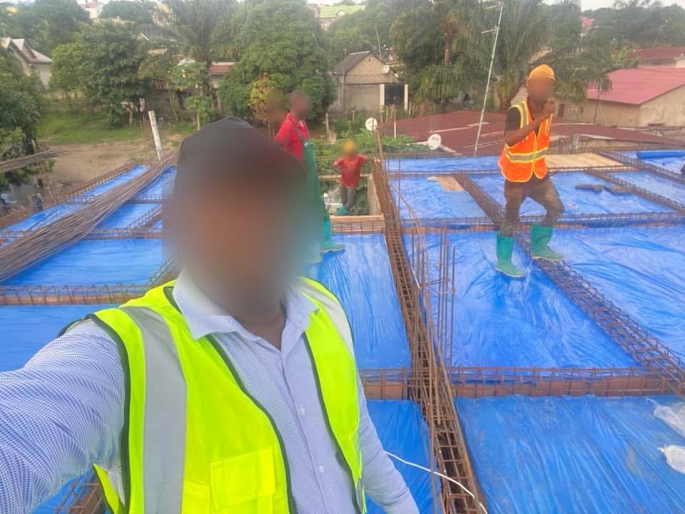 Selfie sur une dalle d'armatures recouverte de bâche bleue, ouvriers en arrière-plan