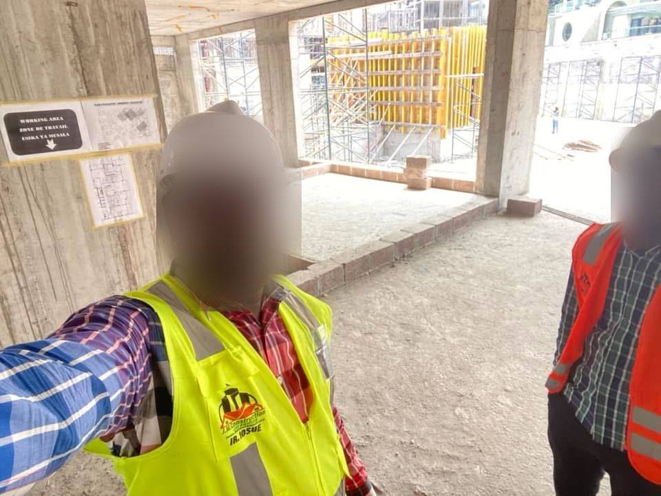 Selfie en gilet jaune à l'intérieur d'un bâtiment en construction, échafaudages en arrière-plan