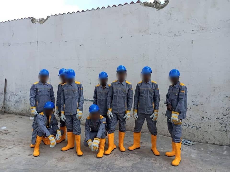 Équipe d'ouvriers en combinaison grise, casques bleus et bottes jaunes