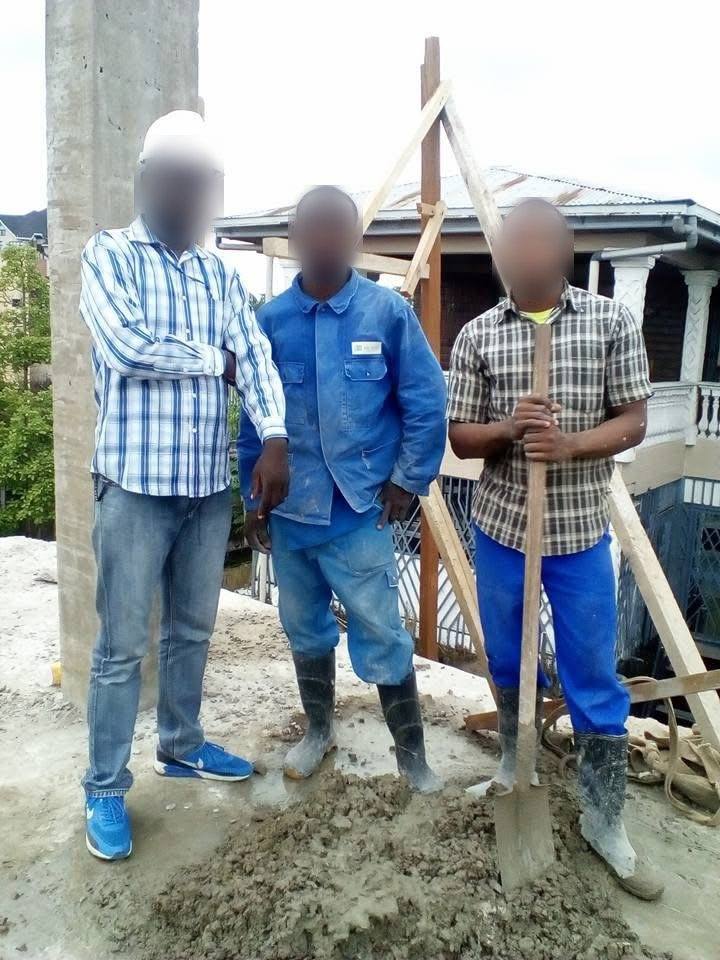 Trois hommes sur une dalle près d'un poteau en béton et d'un échafaudage en bois